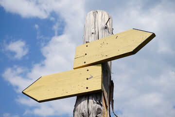 Canvas Print - Wooden signpost with two arrows and sky with clouds in background