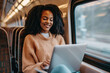 Smiling African American female entrepreneur surfing the net on laptop while traveling by train