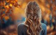 © imagineRbc - A woman with long blonde hair is standing in a forest with leaves on the ground. The leaves are orange and yellow, creating a warm and inviting atmosphere. The woman's hair is styled in a braid