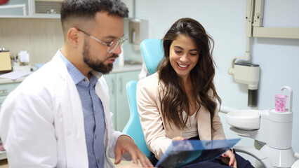 Wall Mural - Young woman at the dentist's listening to her doctor explaining the x-ray of her teeth