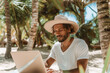Man working with computer at tropical beach on his vacation. Freelance, work from anywhere concept