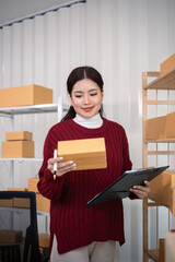 Wall Mural - Young business woman asian working online ecommerce shopping at her shop. Young woman sell prepare parcel box of product for deliver to customer. Online selling