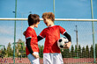 © LIGHTFIELD STUDIOS - Two young men, standing closely together, holding a soccer ball. They appear focused and ready for a game, showcasing teamwork and camaraderie.