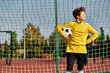 © LIGHTFIELD STUDIOS - A man in a vibrant yellow shirt confidently holds a soccer ball, showcasing his passion for the sport.