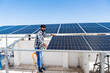 © gajendra - Indian worker installing solar panels on roof of house. Maintenance of photovoltaic panel system. Concept of alternative, renewable energy.