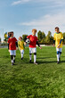 © LIGHTFIELD STUDIOS - A diverse group of enthusiastic young boys stand proudly at the top of a soccer field, looking out at the horizon with determination and joy after a game.