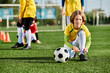© LIGHTFIELD STUDIOS - A young girl energetically plays soccer on a field, confidently dribbling the ball and aiming for the goal.