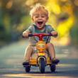 smiling cute little boy is riding his pedal car outdoor in park