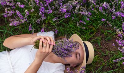 Wall Mural - beautiful girl in a dress holding a bouquet of flowers outdoors in a lavender field in summer.