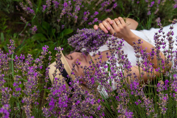 Wall Mural - beautiful girl in a dress holding a bouquet of flowers outdoors in a lavender field in summer.