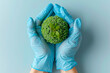 Sustainable health concept with hands in medical gloves holding a green globe shape, World health day concept .