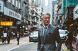 Portrait of mature Asian businessman walking on street in Hong Kong city
