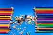 Closeup of row of colorful wooden pencils and sharpened scraps isolated on blue background