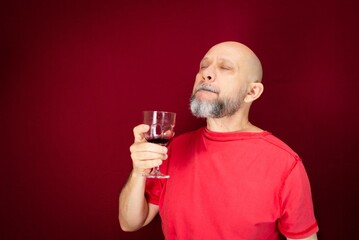 Man holding a glass of wine while standing over a red background