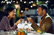 © peopleimages.com - Smile, couple and cheers with wine at restaurant for date, love or holding hands together. Happy man, woman and toast with drink in glass for celebration, anniversary or romance with bokeh at night