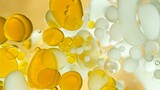 Fototapeta Kuchnia - Freeze Motion Shot of Moving Oil and Milk Bubbles on Golden Background, Cosmetics Concept