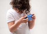 Fototapeta  - Curlyhaired boy holds electric blue gadget in arm