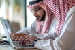 Two arabian man working in an office typing on a laptop