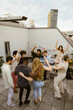 © Maskot - Group of friends dancing on rooftop deck at party