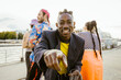 © Maskot - Portrait of smiling non-binary person dancing with friends in background on promenade