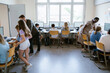 © Maskot - Male and female teacher teaching group of pupils sitting in computer class at school