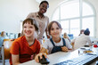 © Maskot - Portrait of smiling girl next to female friend with disability sitting in computer class at school