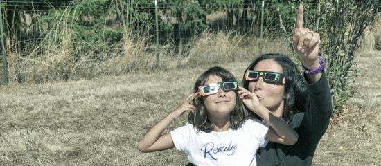 Canvas Print - Mother and daughter, family viewing solar eclipse with special glasses in a park