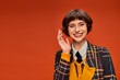 optimistic college girl in checkered uniform waving hand on orange background, happy student life