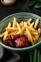 Poster - Chicken skewer with french fries in bowl on black backdrop. Junk food in asian style on dark stone background. Chicken kebab with potatoes in minimal style. Asian skewers of chicken with garnish.