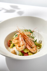 Sticker - Elegant food - salad with shrimp and avocado on white table with harsh shadow. Flashy food concept. Seafood salad with shrimp, tomatoes and avocado on white plate with sunlight.