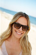 © peopleimages.com - Woman, sunglasses and travel to beach on vacation, smile and peace on sand or relax by water. Female person, happy and tropical ocean for tranquil on weekend, outdoor nature and confident by ocean