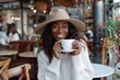 Attractive african american woman in white sweater and hat holding cup of coffee in cafe