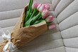 Bouquet of fresh pastel pink tulips wrapped in the craft paper decorated with satin ribbon