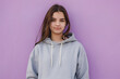 © MAKSIM MAKSIMOV - Young woman in gray hoodie on purple background