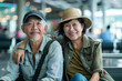 Happy Asian couple sitting and waiting happily at the airport to catch their retirement trip.