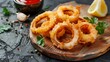 Rings of squid in batter with sauce on the board on dark concrete rustic background