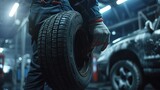 Fototapeta  - Car mechanic is holding tire in hand and is ready for changing tires. copy space for text.