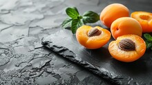   A Collection Of Ripe Apricots Atop A Slate Countertop, Adjacent To Verdant Foliage