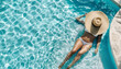 Young woman in stylish sunhat and bikini relaxes in shimmering pool, enjoying serene moment of leisure. The crystal-clear water reflects sunlight, creating a tranquil atmosphere. Vacation concept.
