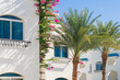 Mediterranean-style white building adorned with vibrant pink bougainvillea under a clear blue sky.
