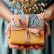 Close-Up of Hands Presenting a Colorfully Wrapped Gift With a Pink Ribbon.