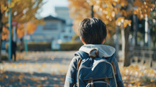 Child With A Backpack Walking On A Path Lined With Golden Autumn Leaves.