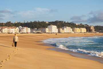 Wall Mural - Woman walking on Nazaré Beach and Atlantic Ocean, Portugal