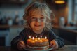 Cheerful young child holding a birthday cake with lit candles in a dimly lit room, excited eyes