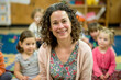 © PixelGallery - Portrait of teacher smiling at camera in classroom with children in background