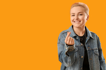 Poster - Young woman with short hair making heart with her fingers on yellow background