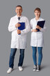 © Pixel-Shot - Mature doctor and his assistant with clipboards on light background