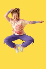 Wall Mural - Beautiful young happy woman dancing hip-hop on yellow background