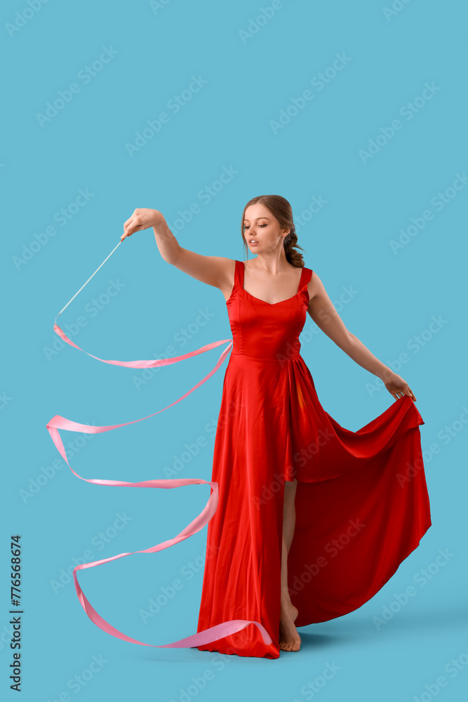 Beautiful young woman with ribbon dancing on blue background