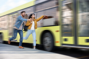 Being late. Couple running after bus outdoors. Motion blur effect